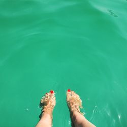 Low section of woman relaxing in swimming pool during summer