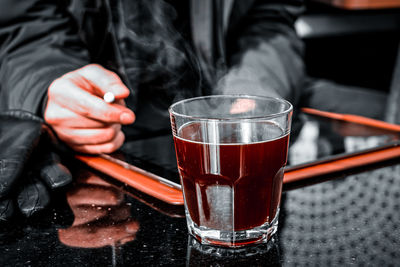 Midsection of man holding drink on table