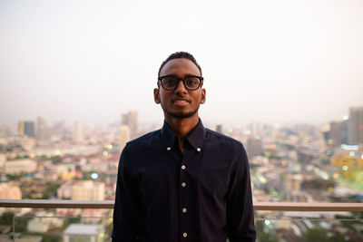 Portrait of young man standing against cityscape