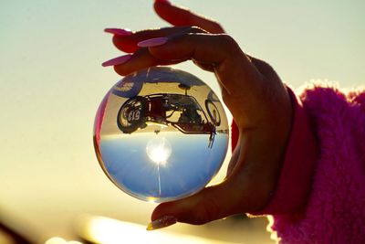 Close-up of person holding camera against sky