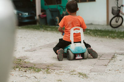 Rear view of boy playing with toy car on street