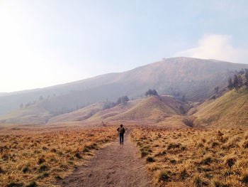 Rear view of man walking on desert against mountain