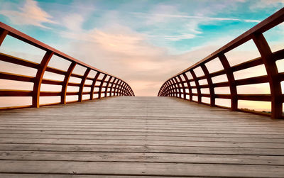 Surface level of wooden footbridge against sky