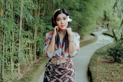 Young woman standing against plants