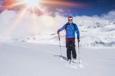 Full length of smiling man standing on snow covered landscape