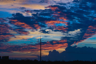 Low angle view of silhouette trees against dramatic sky