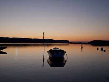 Boat on lake against sky during sunset