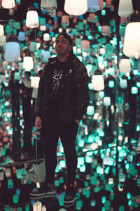 Full length of young man standing against illuminated lights