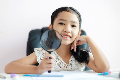 Portrait of a smiling girl sitting against wall