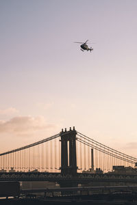 Low angle view of helicopter flying over manhattan bridge