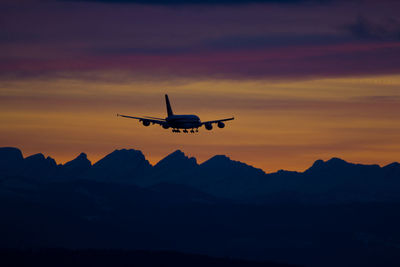 Silhouette airplane flying against sky during sunset