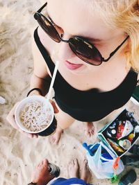 High angle view of woman holding sunglasses at beach