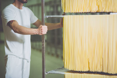Midsection of worker pushing trolley fresh spaghetti in factory
