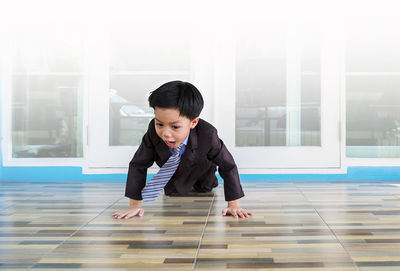 Boy shouting while crawling on tiled floor