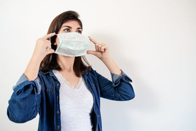 Portrait of woman holding covering face against white background
