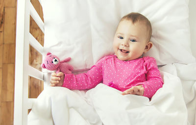 Portrait of cute baby girl lying on bed at home