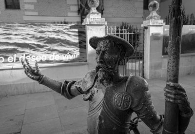 Statue of woman holding sculpture in city