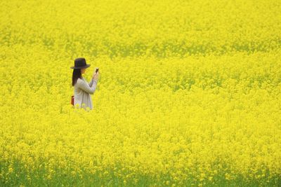 Young woman with yellow flowers in field