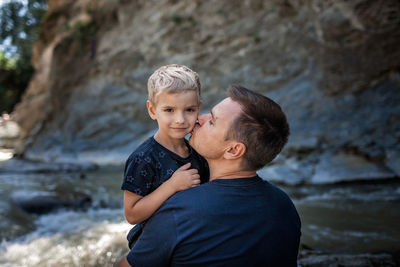 Like father like son. middle aged father embracing cute little son on the bank of river