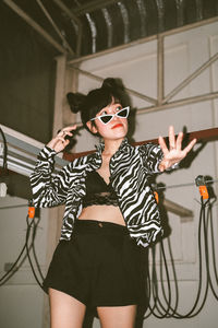 Midsection of woman wearing sunglasses standing against wall