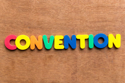 Directly above shot of colorful alphabets making convention text on table