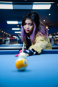 Young woman playing pool at home