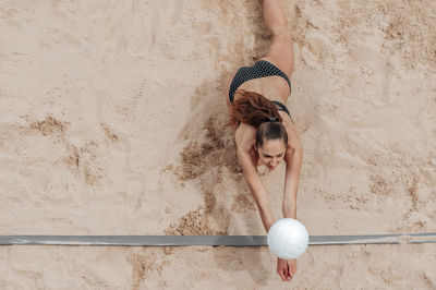 High angle view of woman playing volleyball on sand at beach