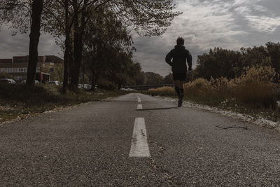 Rear view of man walking on road