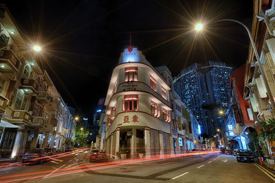 Illuminated street amidst buildings in city at night