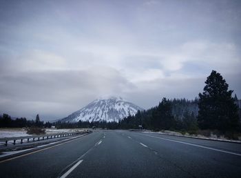 Road by mountains against sky during winter