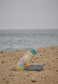 Deck chairs on shore at beach against sky