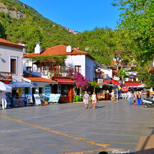 building exterior, architecture, built structure, street, tree, person, house, mountain, residential structure, road, men, walking, town, lifestyles, residential building, clear sky, city, sunlight, large group of people