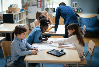 Teacher explaining children sitting in classroom at school