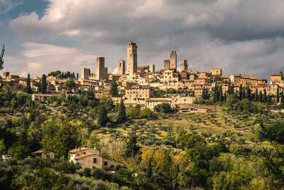 View of medieval tuscany hilltown san gimignano against cloudy sky, italy