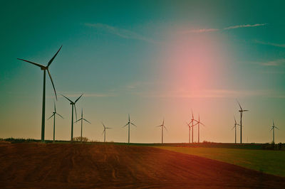 Wind turbines on field against sky