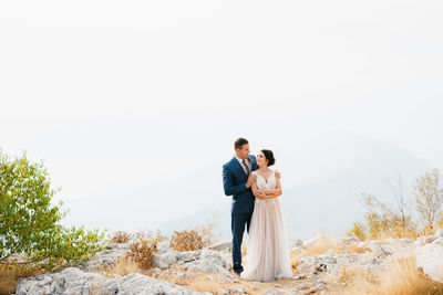 Front view of couple standing on rock