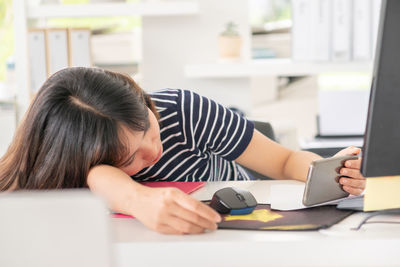 Rear view of woman using phone while sitting on table