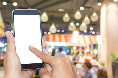 Close-up of hand holding smart phone in restaurant