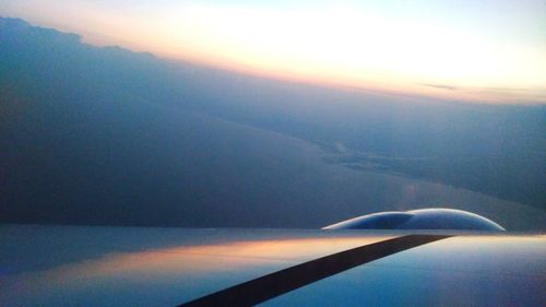 Close-up of airplane wing over landscape against sky