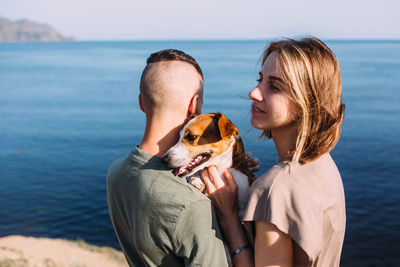 Happy couple with favourite pet. young man and woman have walk near sea.