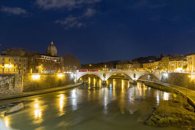 Arch bridge over river at night