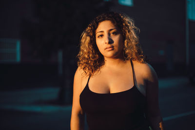 Portrait of seductive young woman with curly hair in dark