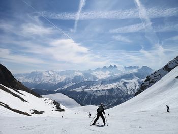 Man skiing on snowcapped mountain against sky