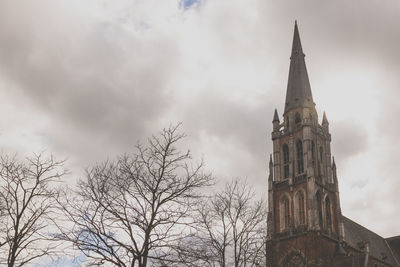 Low angle view of clock tower against cloudy sky