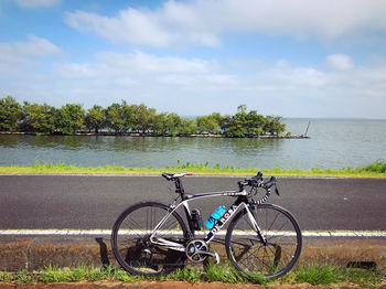 Bicycle by sea against sky