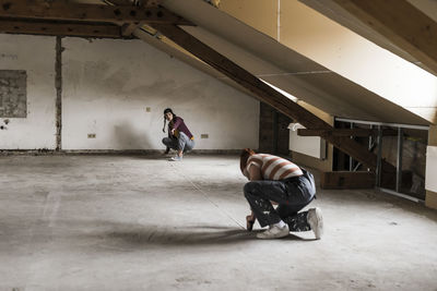 Young man and woman measuring floor on construction site