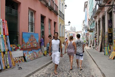 Rear view of people walking on street amidst buildings