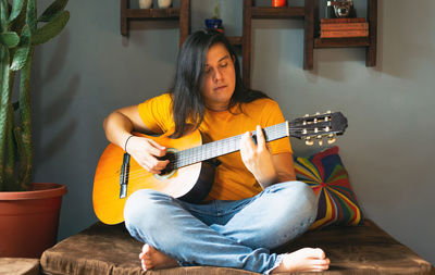 Young woman playing guitar at home