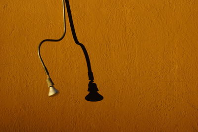 High angle view of light bulb hanging against yellow wall