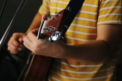 Midsection of man playing guitar